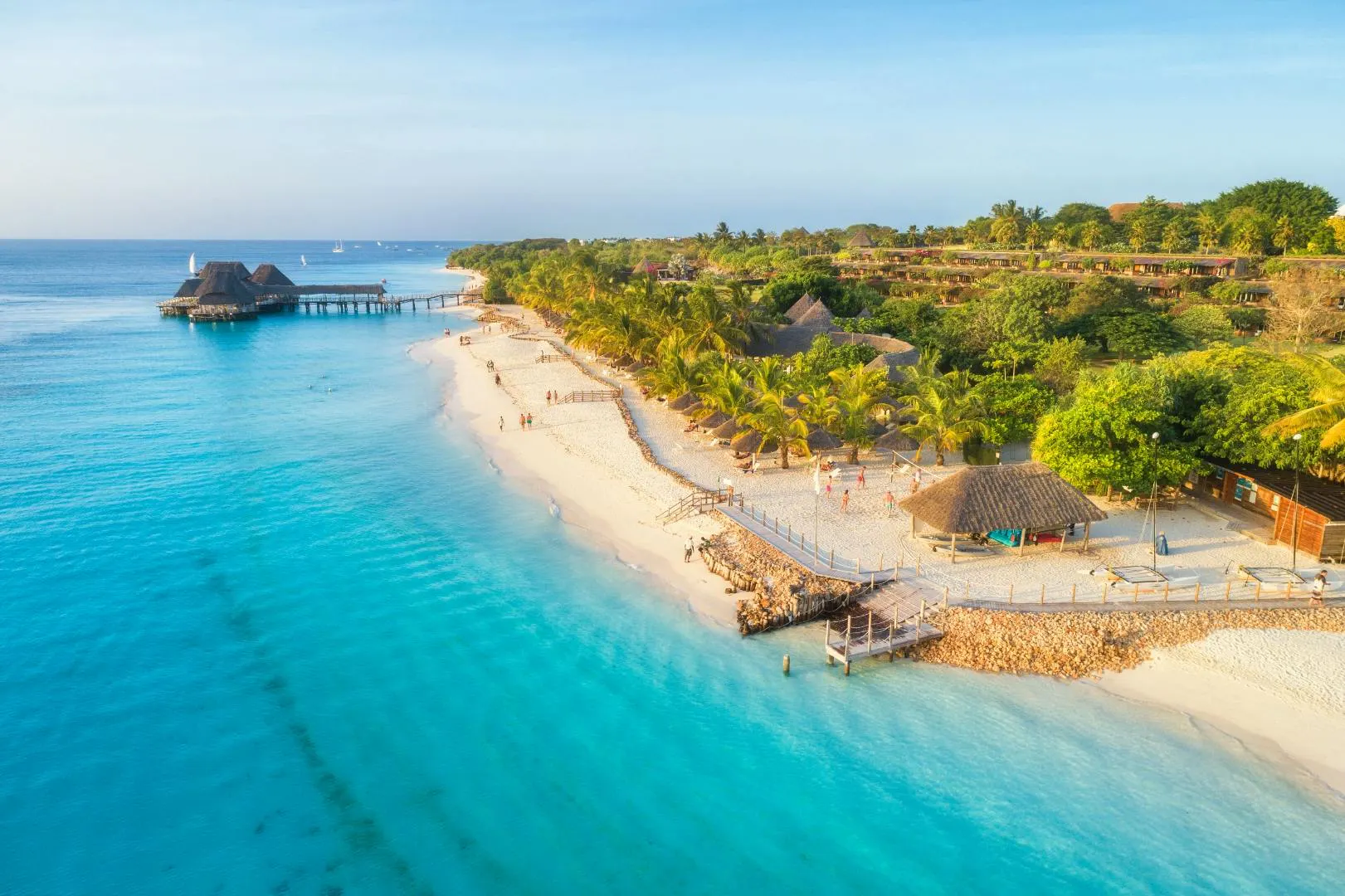 Veduta aerea di una spiaggia tropicale con sabbia bianca, acque cristalline e vegetazione costiera