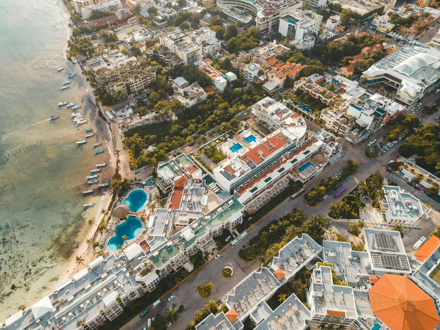 Veduta aerea di una città costiera con hotel, piscine e spiaggia sul mare turchese