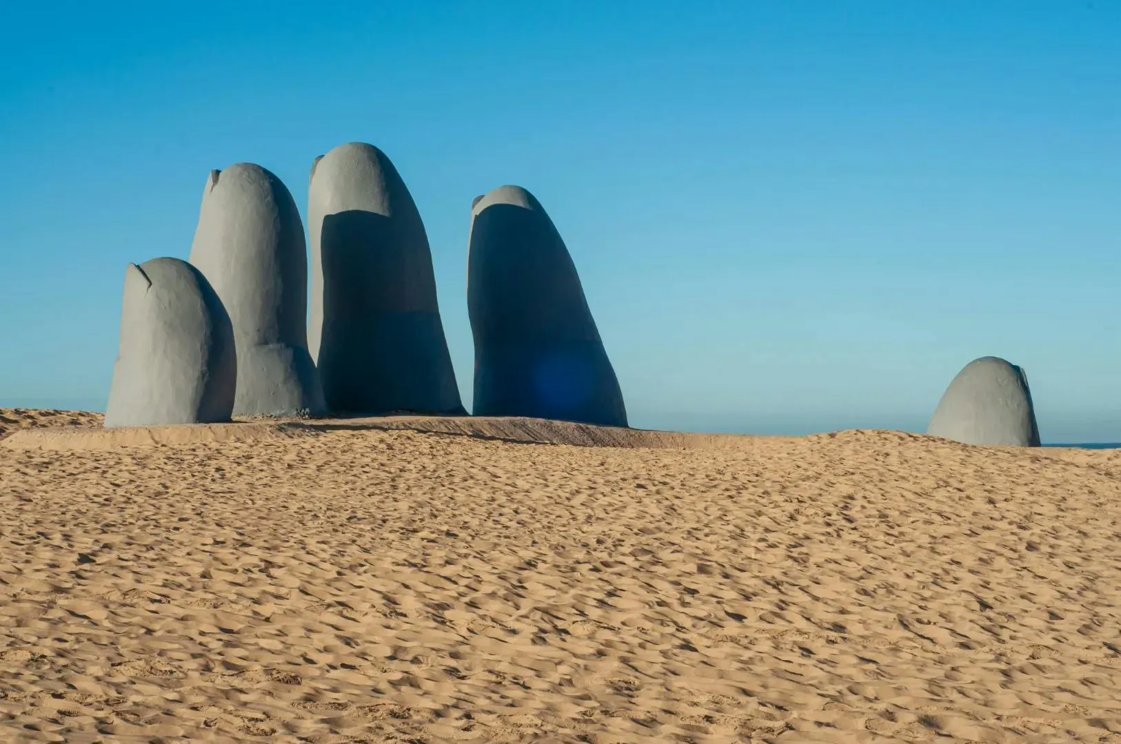 Scultura moderna su una spiaggia in Uruguay sotto un cielo azzurro e sereno