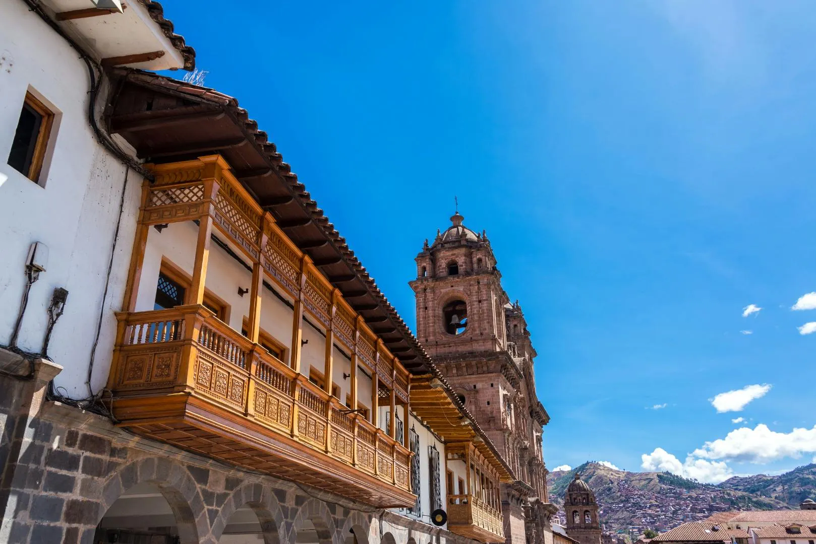 Strada coloniale in Perù con balconi in legno e una chiesa storica sullo sfondo