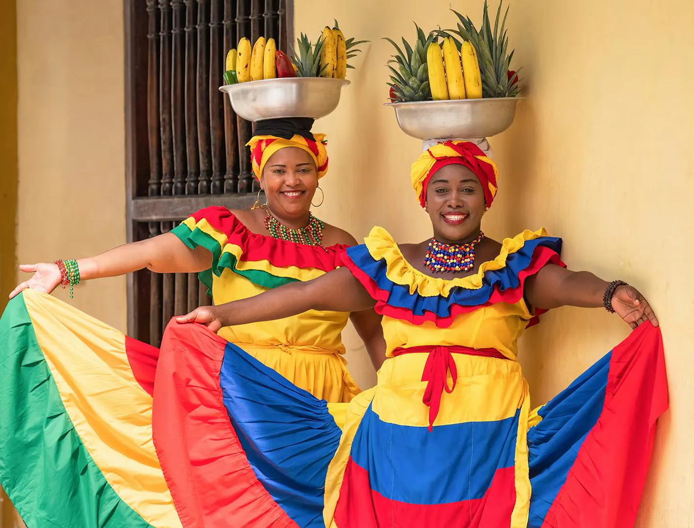 Donne in abiti tradizionali colorati che posano davanti a un edificio in stile coloniale