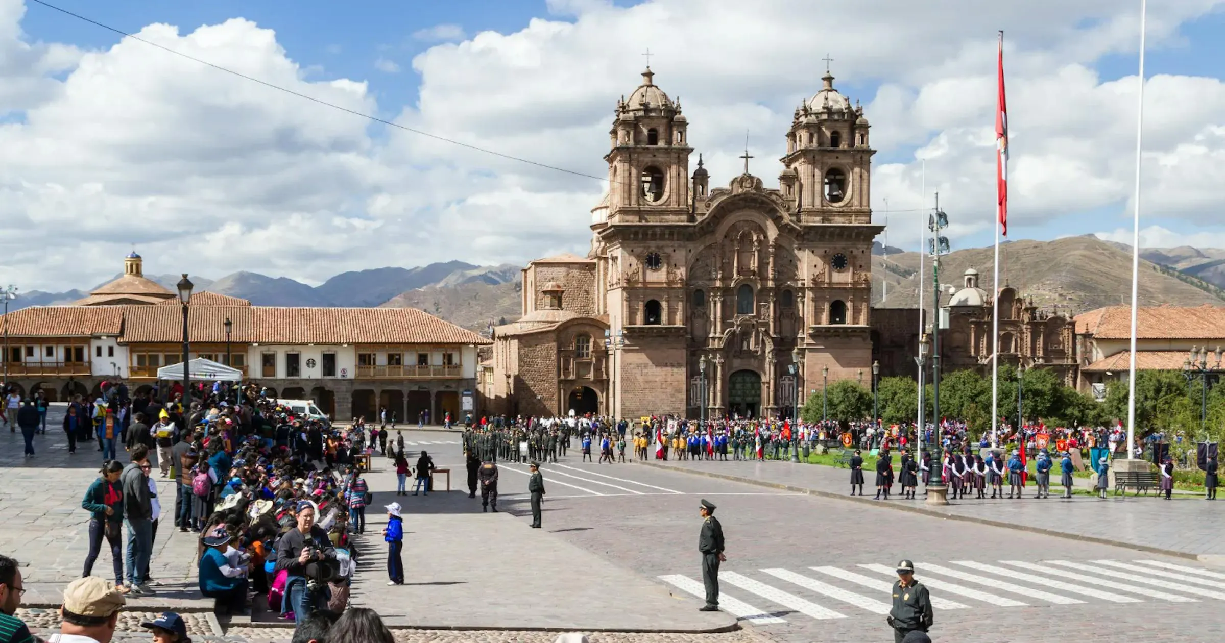 Piazza storica a Cusco con una cattedrale coloniale e persone che passeggiano nel centro città