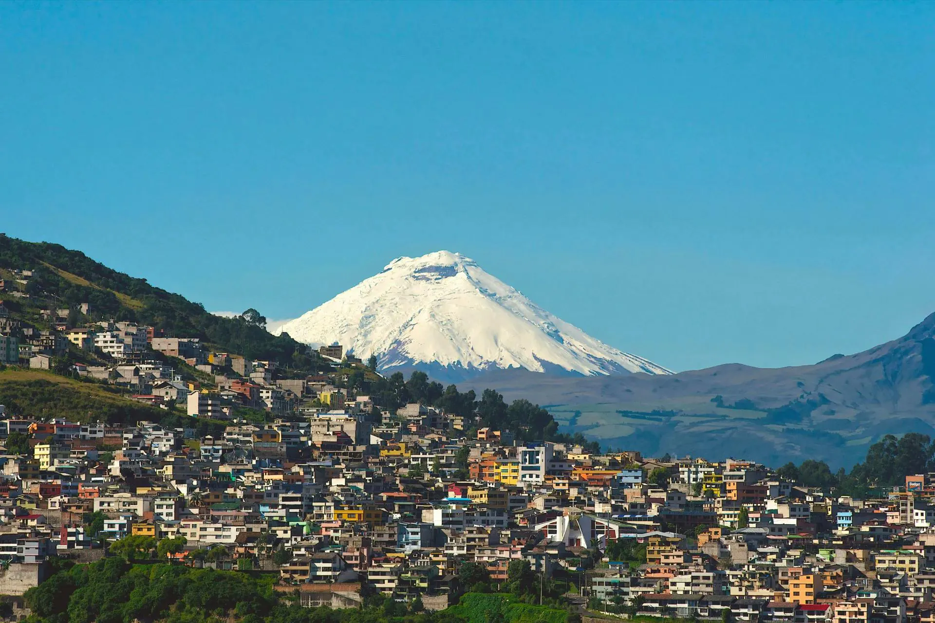 Veduta di Quito con il vulcano Cotopaxi innevato sullo sfondo sotto un cielo sereno