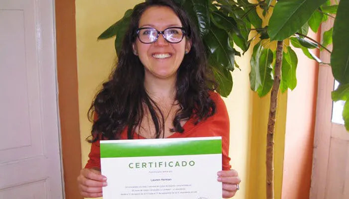 Studente che sorride mentre tiene un certificato di completamento del corso.