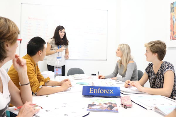 Lezione in piccolo gruppo multiculturale con studenti e un insegnante in una scuola Enforex, che imparano insieme in un ambiente di classe interattivo