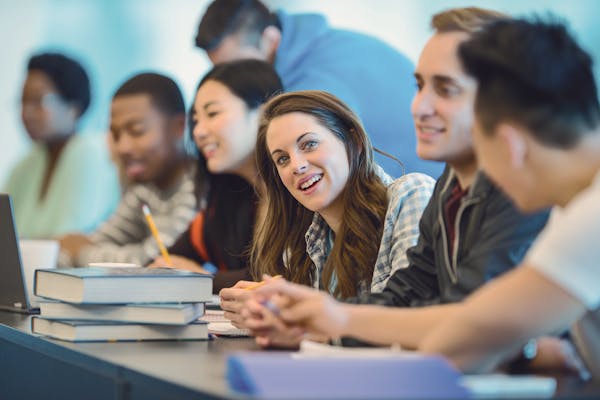 Clase multicultural de español con estudiantes internacionales diversos y un alumno sonriente