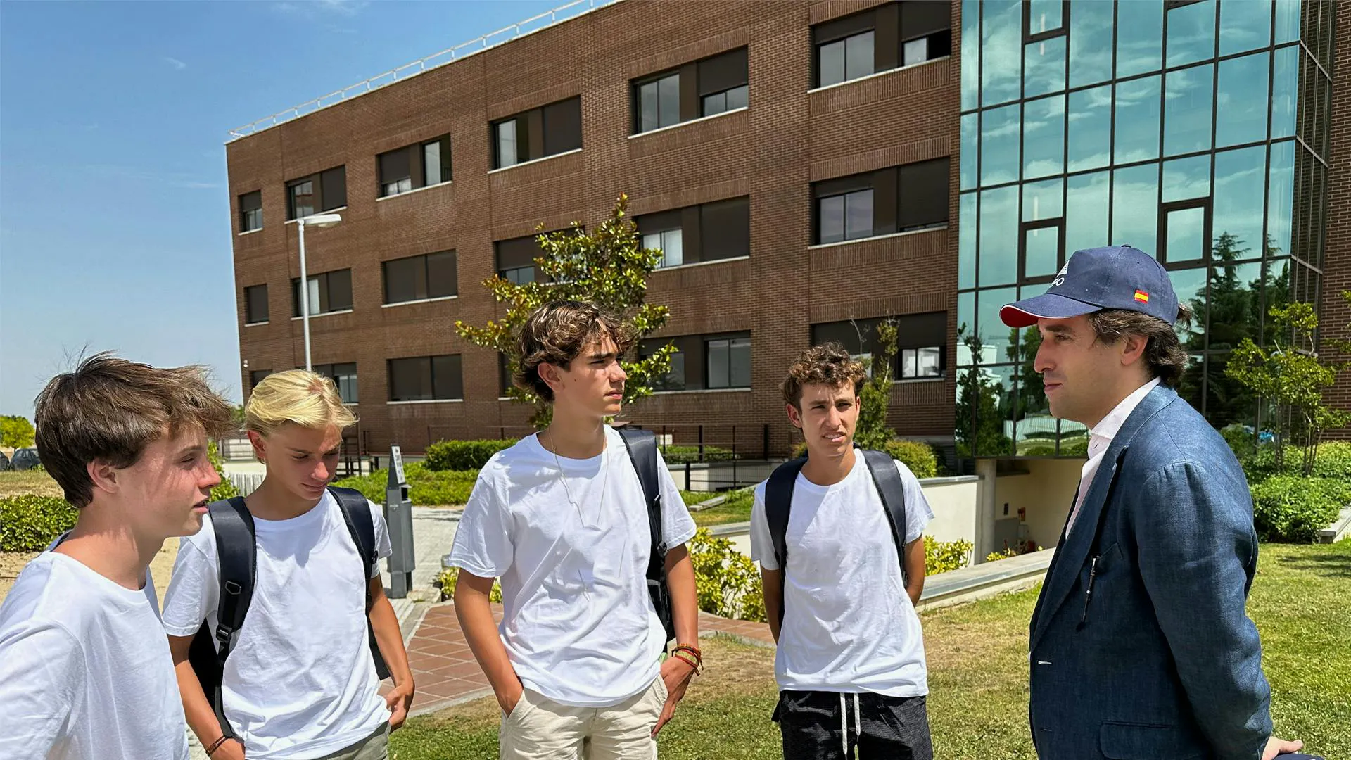 Gruppo del programma di leadership di quattro studenti con Fernando Alonso, davanti al campus dell'Universidad Francisco de Vitoria.