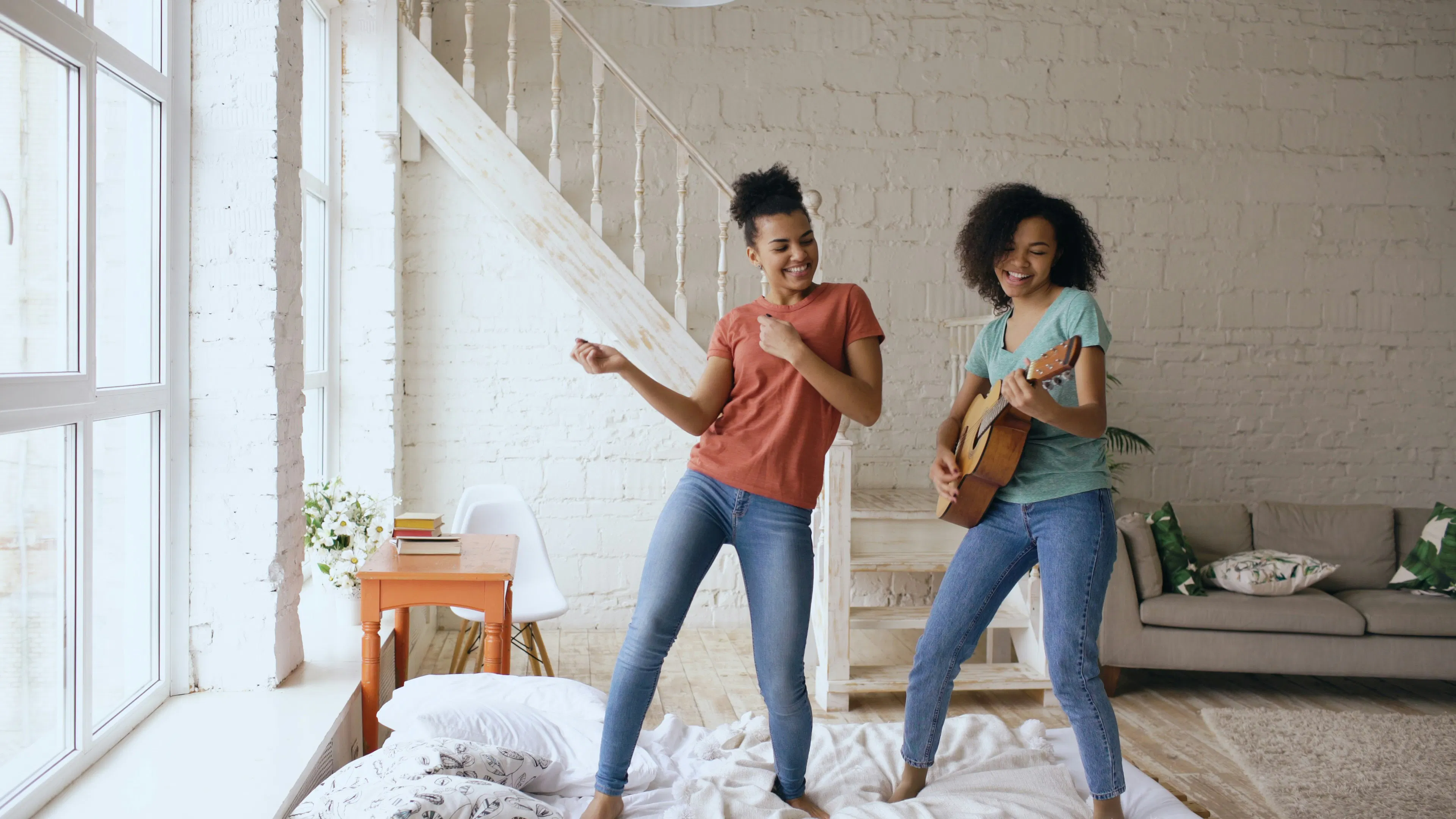Due donne che ballano e suonano la chitarra al chiuso.