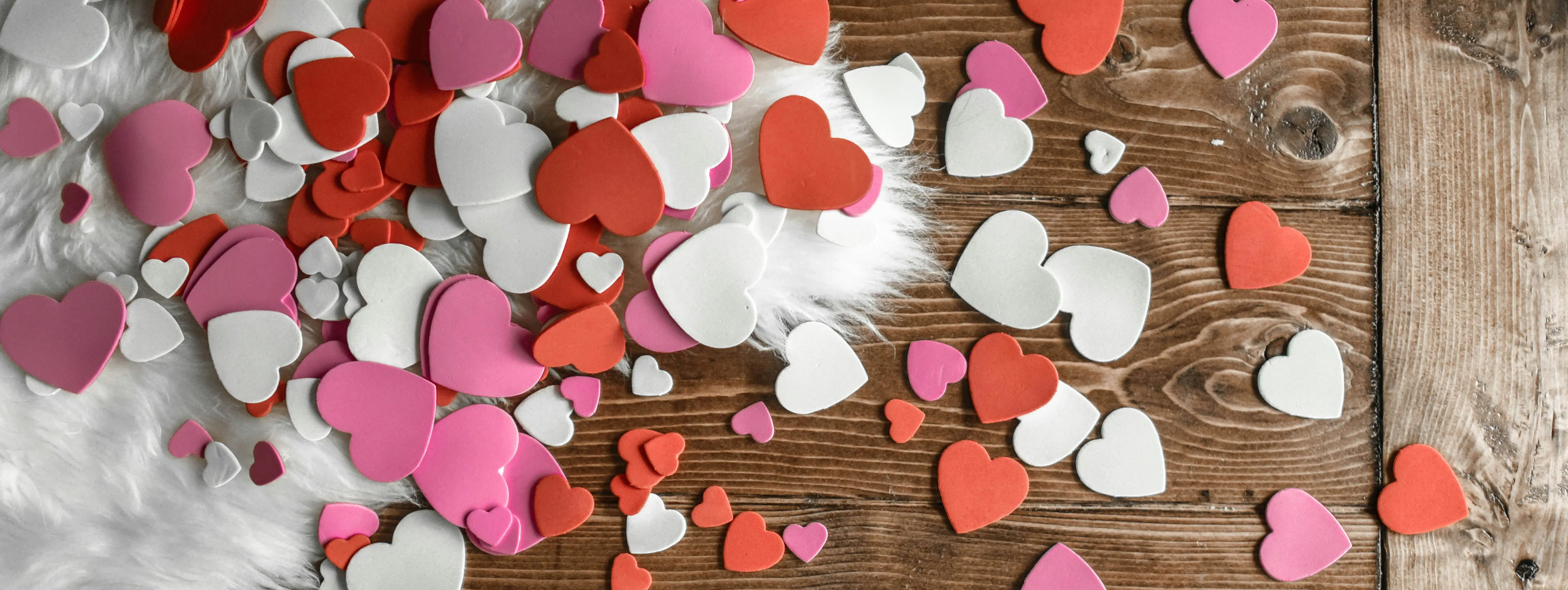 decorazioni ritagliate di vari colori a forma di cuore posizionate su una superficie di legno
