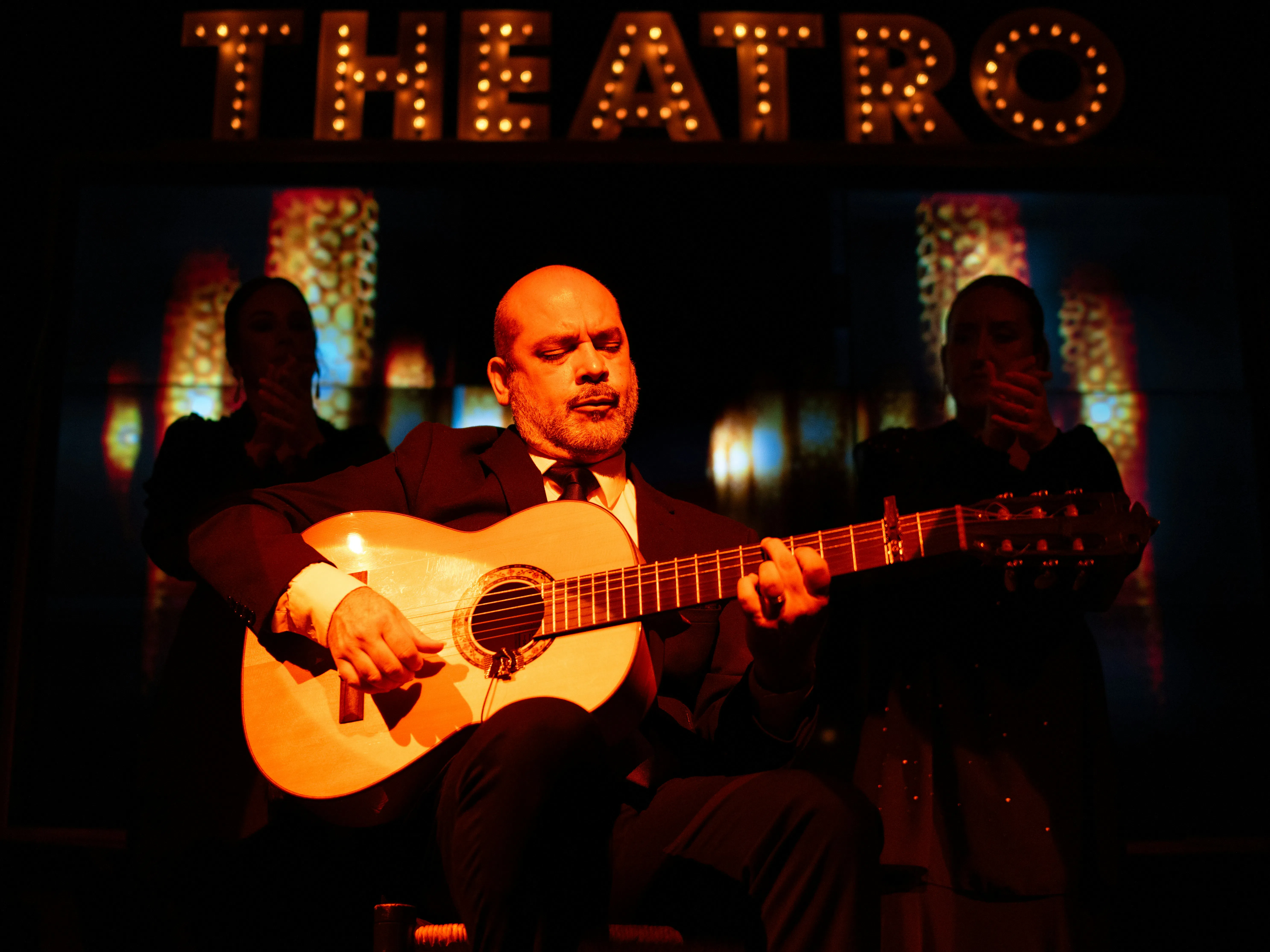 رجل يعزف على الجيتار تحت لافتة "theatro"