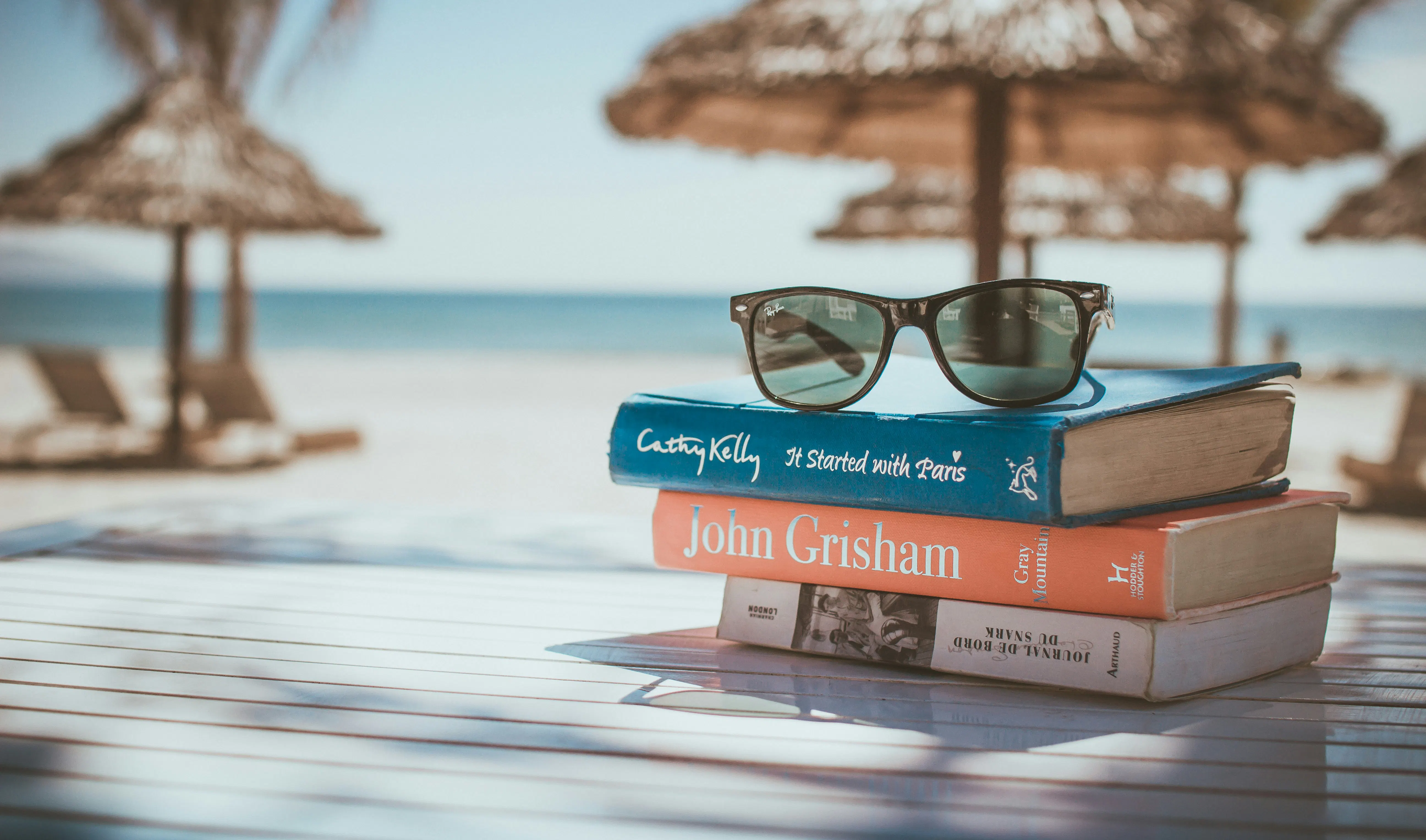 occhiali da sole Ray-Ban Wayfarer con montatura nera sopra un libro