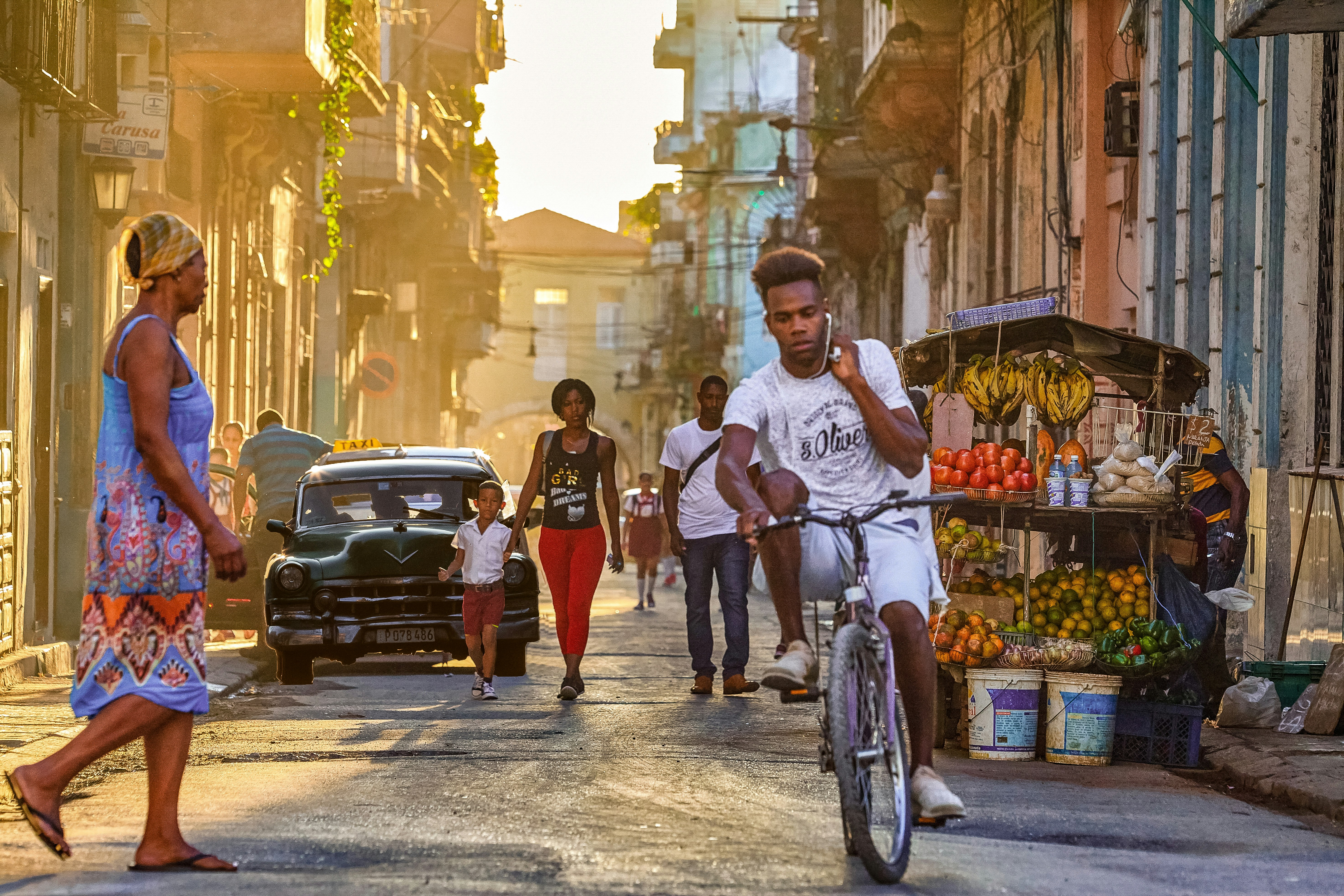 uomo in t-shirt bianca a girocollo che pedala su una bicicletta per strada durante il giorno