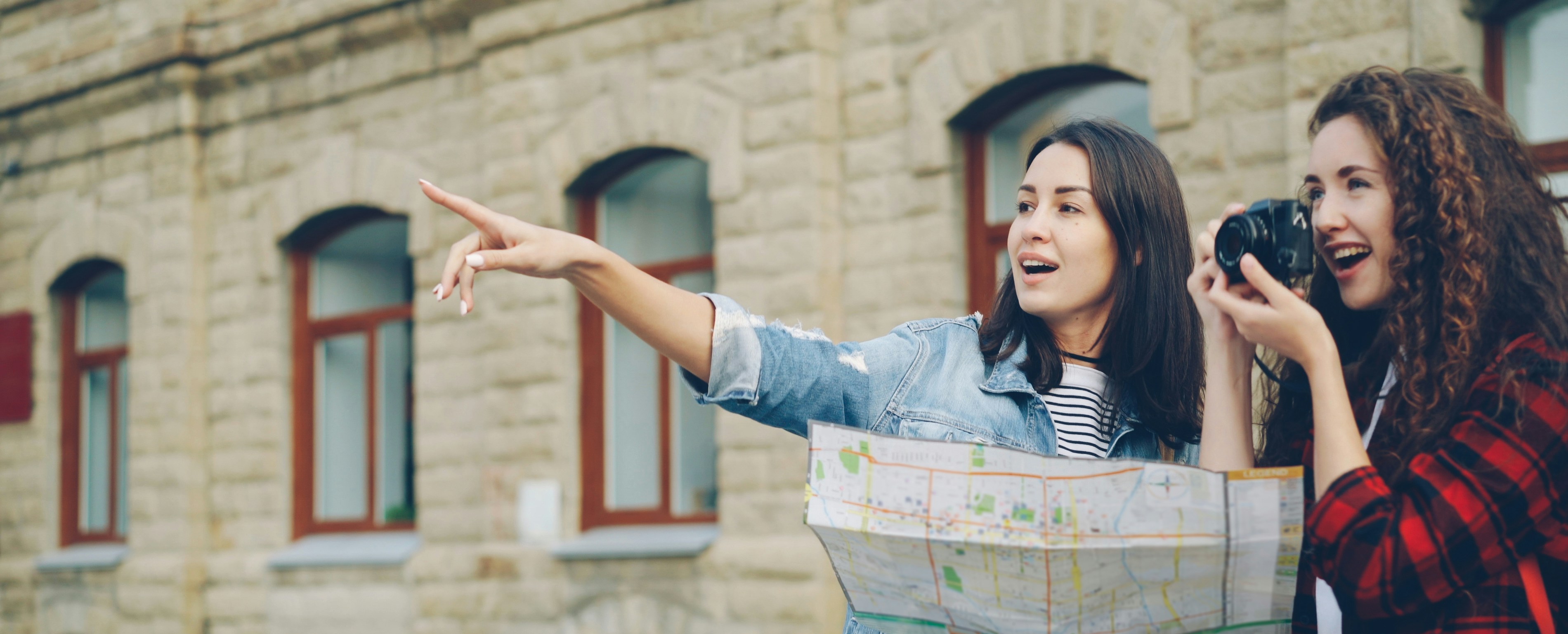 二人の女性が地図とカメラを持って観光しています。