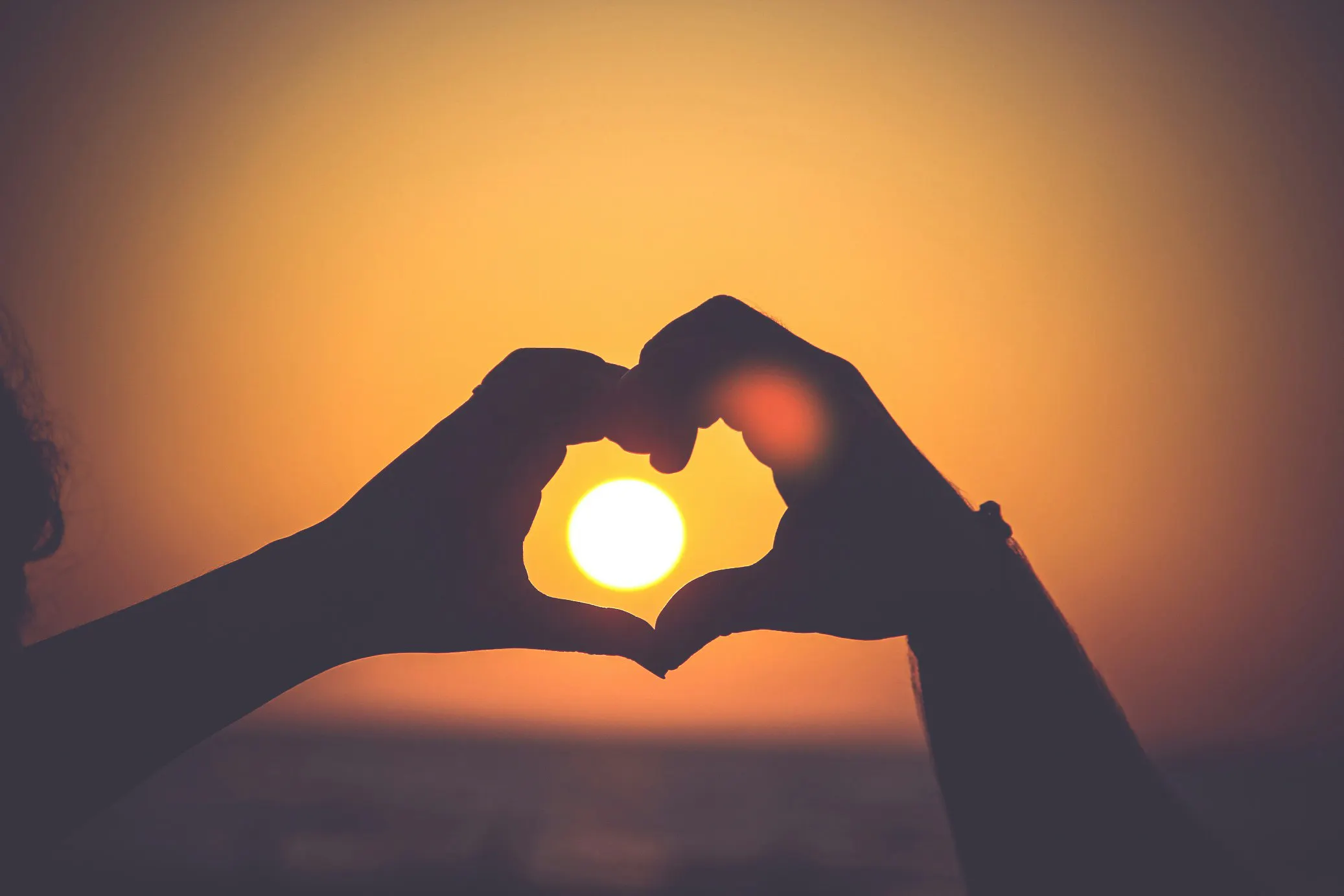silhouette delle mani di una persona che formano un cuore