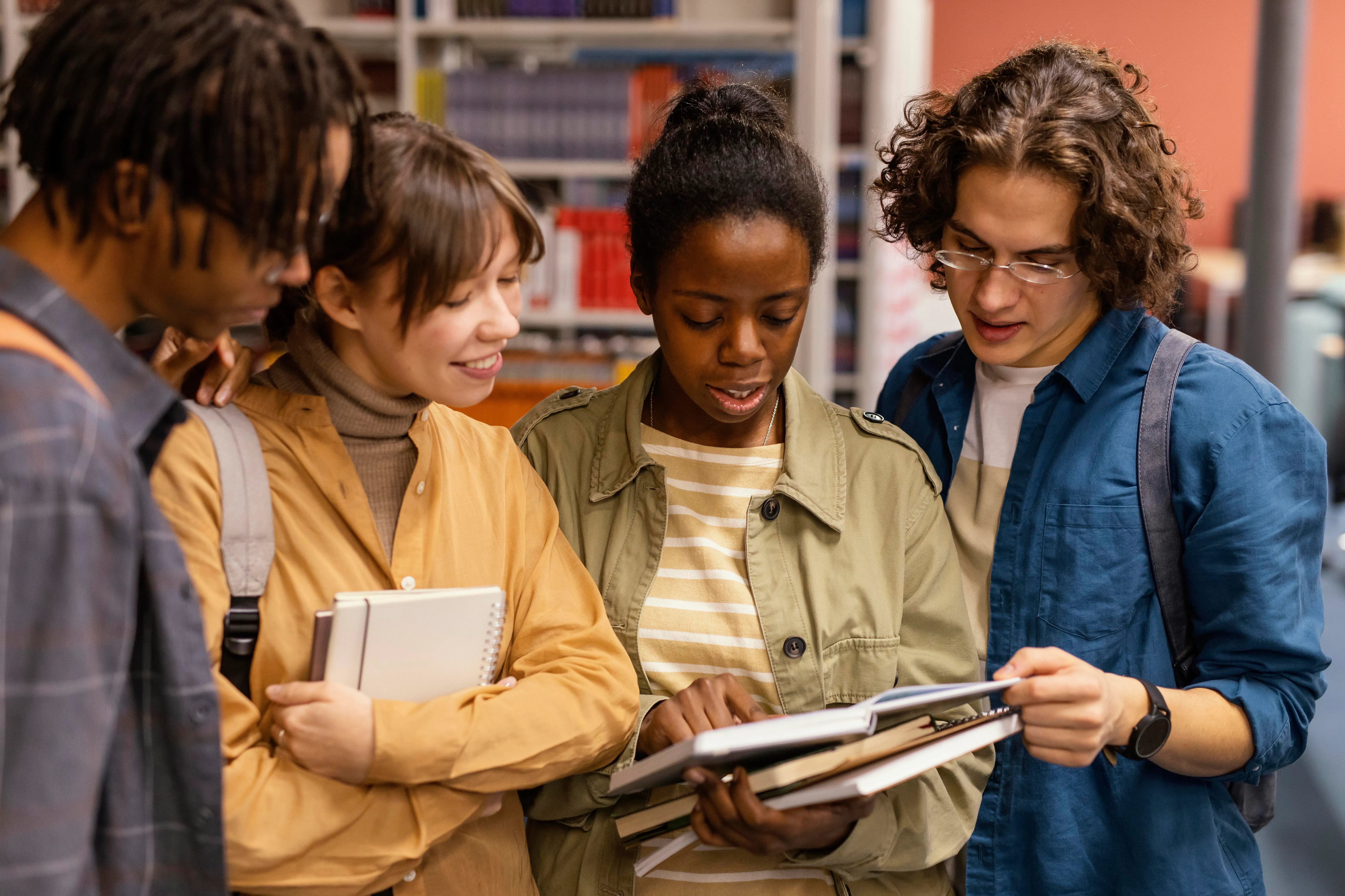 quatro jovens conversando e olhando livro