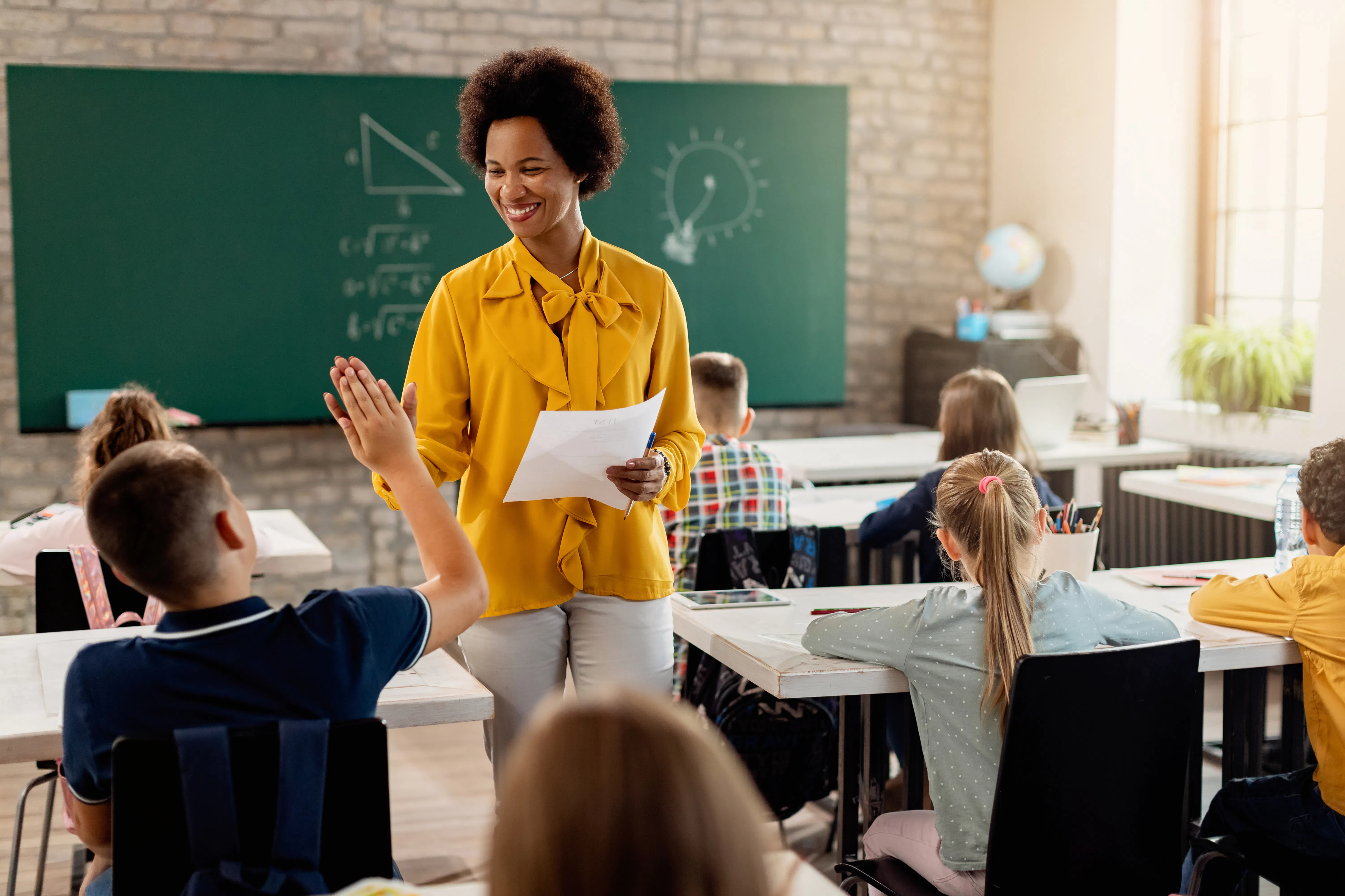 Mulher dando aula em uma sala de aula e explicando conteúdo