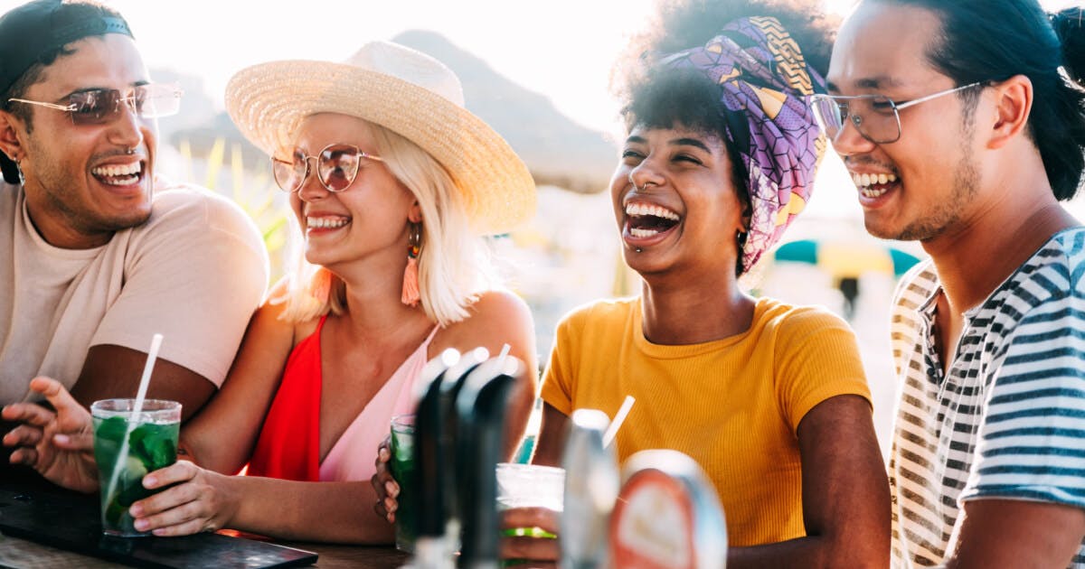 Grupo de amigos sorrindo e rindo juntos em um bar, desfrutando de momentos de alegria e camaradagem.