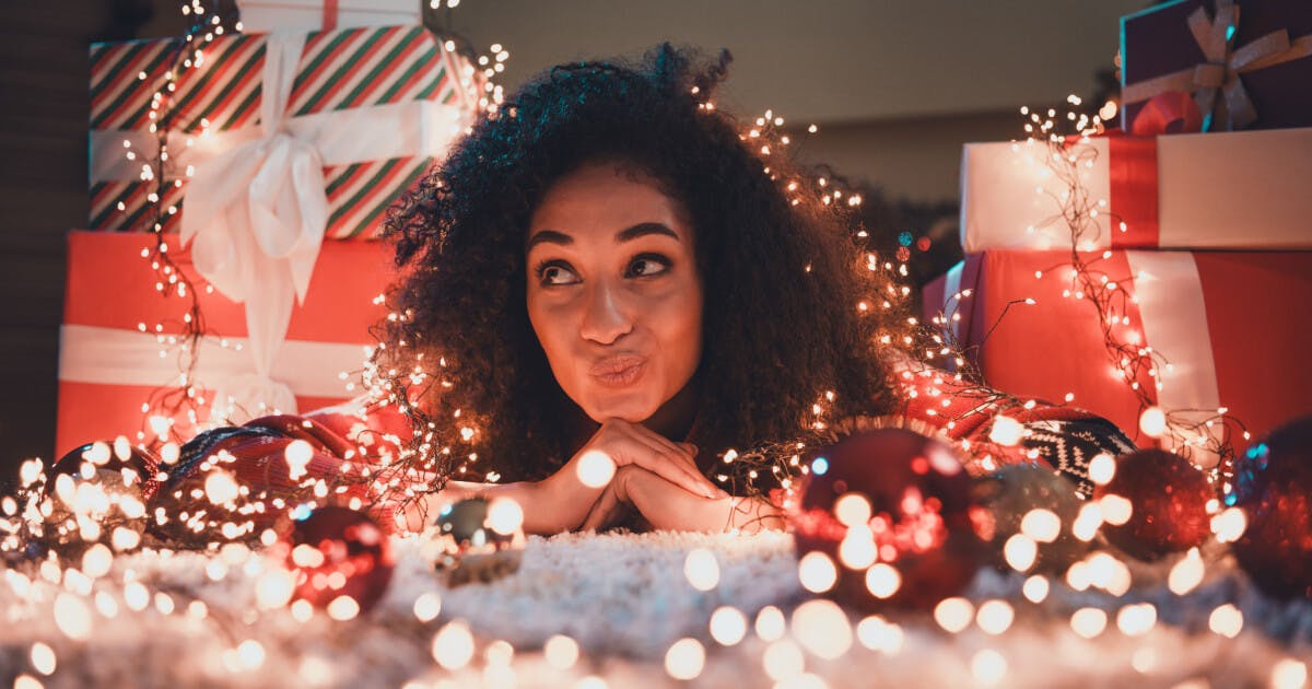 Uma mulher com cabelo cacheado adornada com luzes de Natal, criando um ambiente festivo e acolhedor.