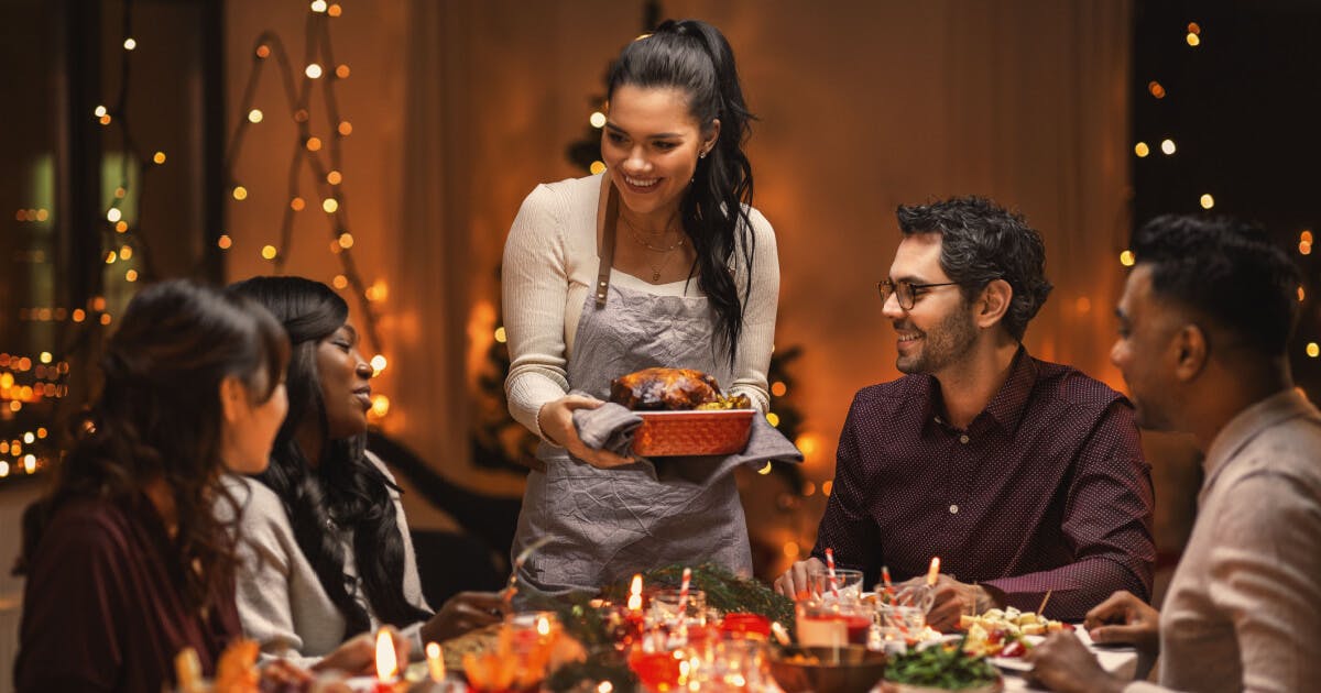 Uma mulher servindo um peru para sua família durante um jantar de Natal.