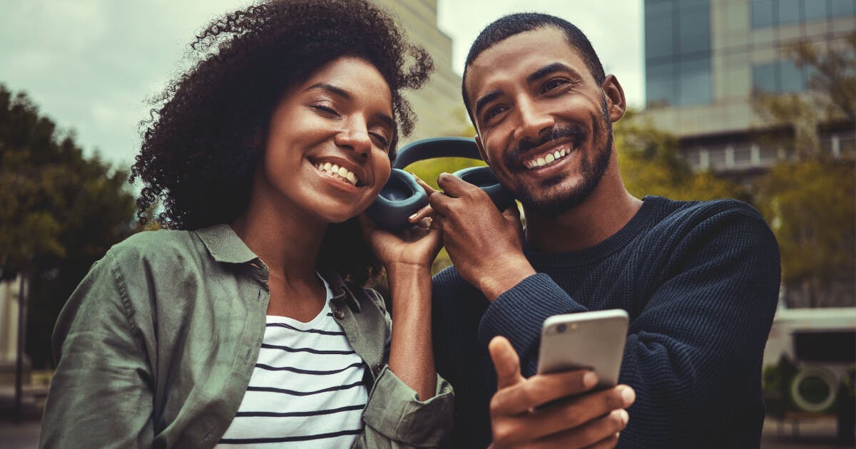 Um homem e uma mulher sorriem enquanto seguram um celular, transmitindo alegria e conexão.