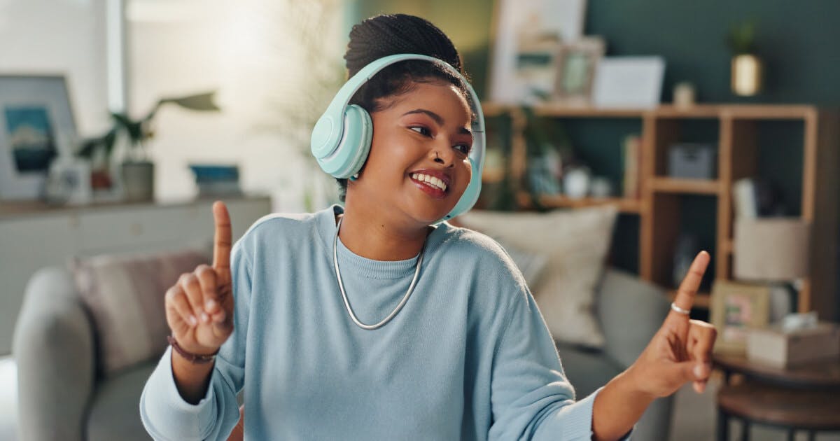 Uma mulher sorridente usando fones de ouvido enquanto ouve música.