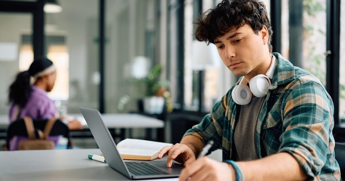 Homem com fones de ouvido trabalhando em seu laptop, concentrado em suas atividades.