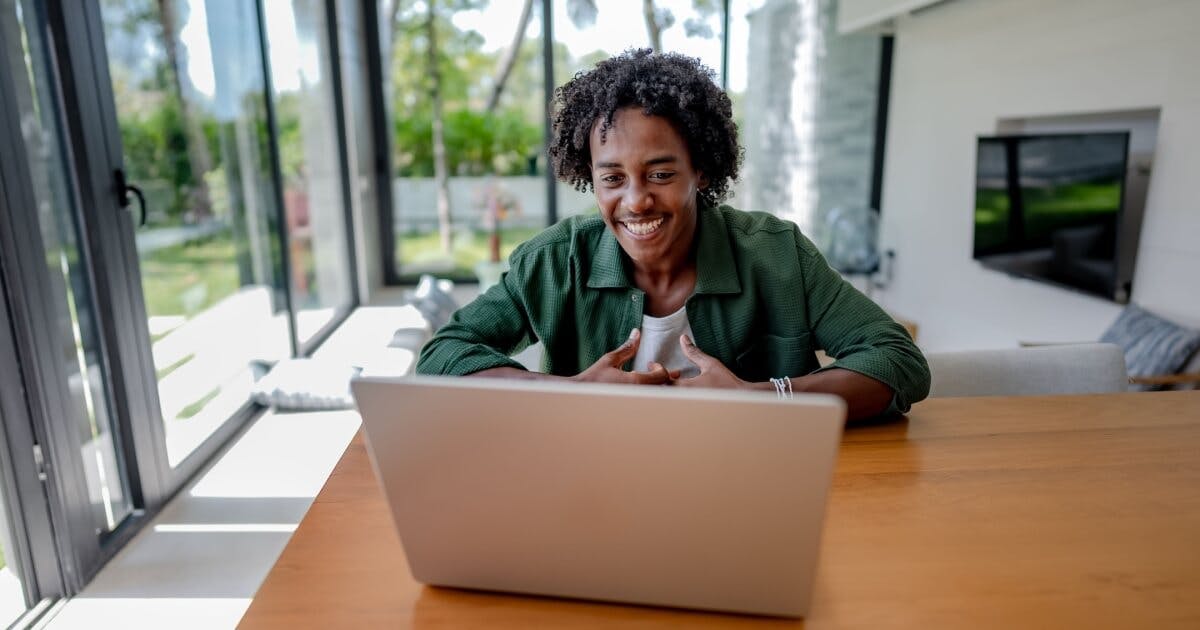 Uma mulher sorri enquanto utiliza seu laptop, transmitindo alegria e concentração em seu trabalho.