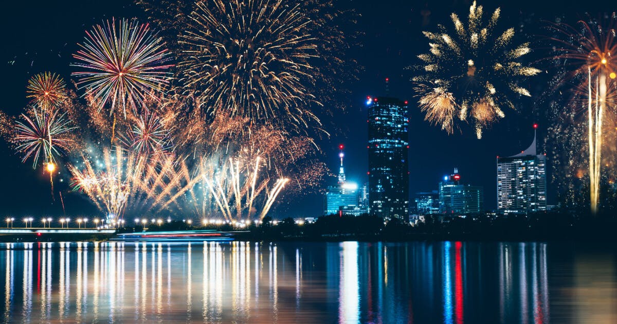 Fogos de artifício iluminando o horizonte da cidade à noite, criando um espetáculo colorido no céu.