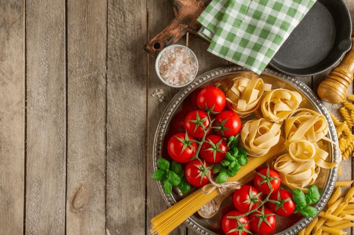 Foto de tomates, massas de macarrão, sal e outros elementos gastronômicos