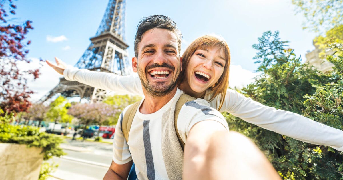 Casal tirando uma selfie em frente à Torre Eiffel, capturando um momento especial em Paris.