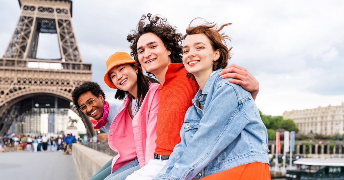 Três jovens posando para uma foto em frente à Torre Eiffel, capturando um momento de alegria e amizade.