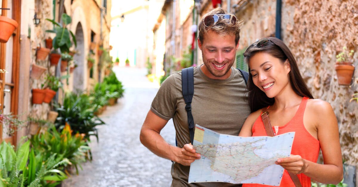 Um homem e uma mulher observam um mapa em um beco, demonstrando interesse e curiosidade sobre o local.