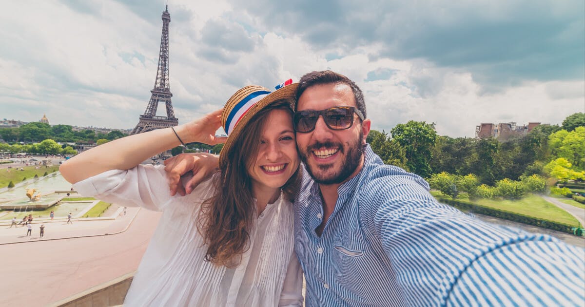 Casal tirando uma selfie em frente à Torre Eiffel, capturando um momento especial em Paris.