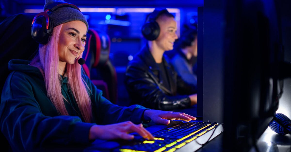 Uma mulher com cabelo rosa jogando em um computador.