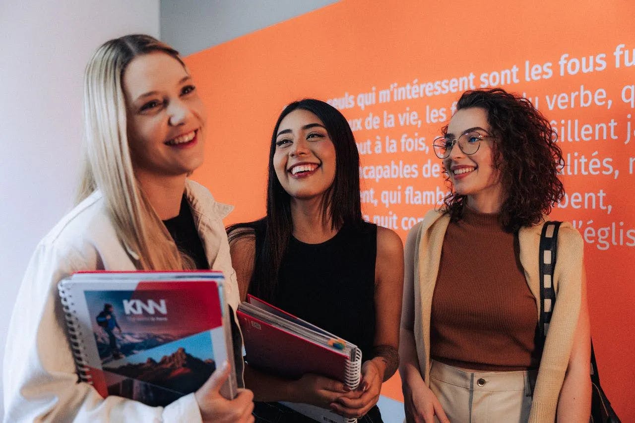 3 mulheres sorrindo enquanto seguram livros da KNN