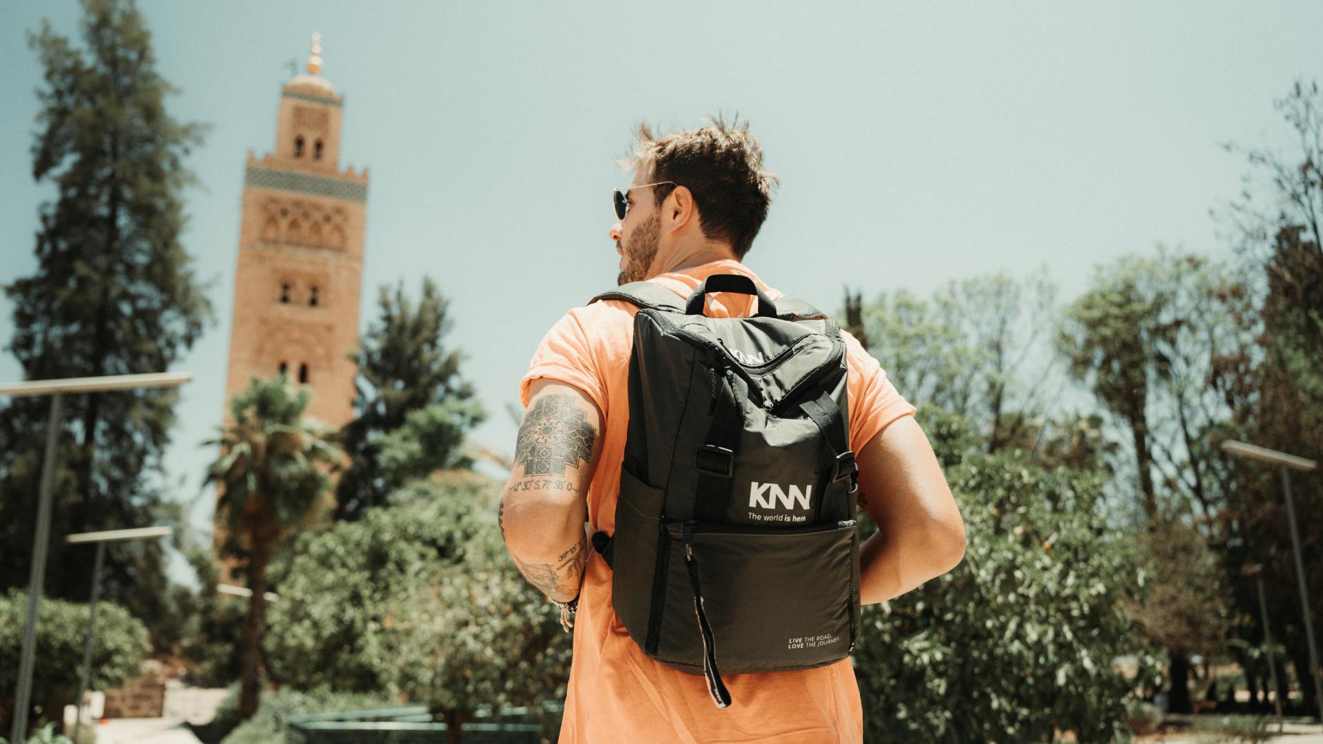 Imagem do Gean Skrebsky, da KNN Idiomas, com uma mochila preta nas costas e uma camiseta laranja.