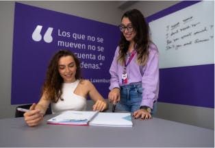 Mulher escrevendo em um livro KNN com a professora ao seu lado