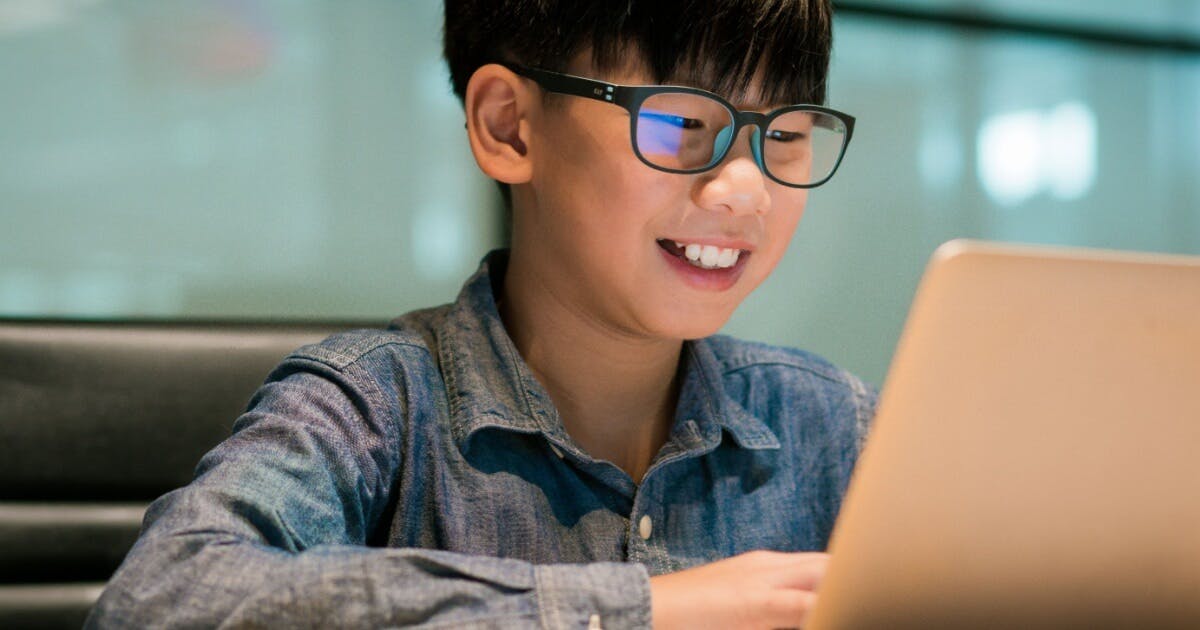 Criança sorrindo e feliz jogando em um notebook