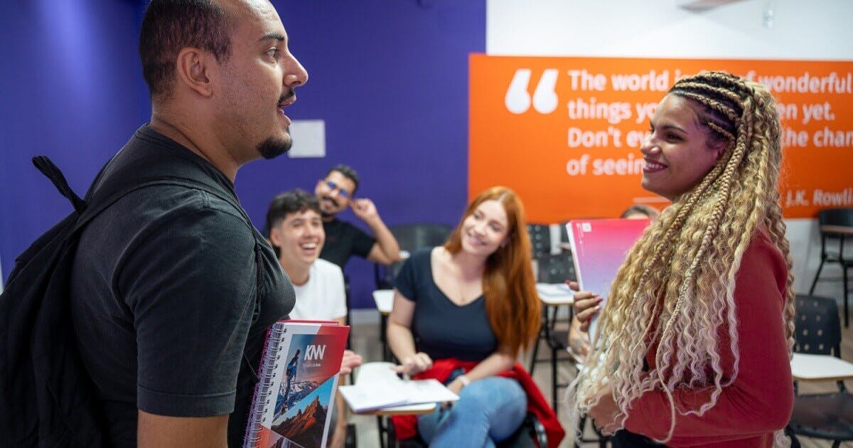 Alunos conversando e sorrindo dentro de uma sala de aula