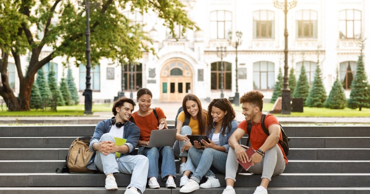 Um grupo de jovens estudantes sorrindo e olhando para um livro.