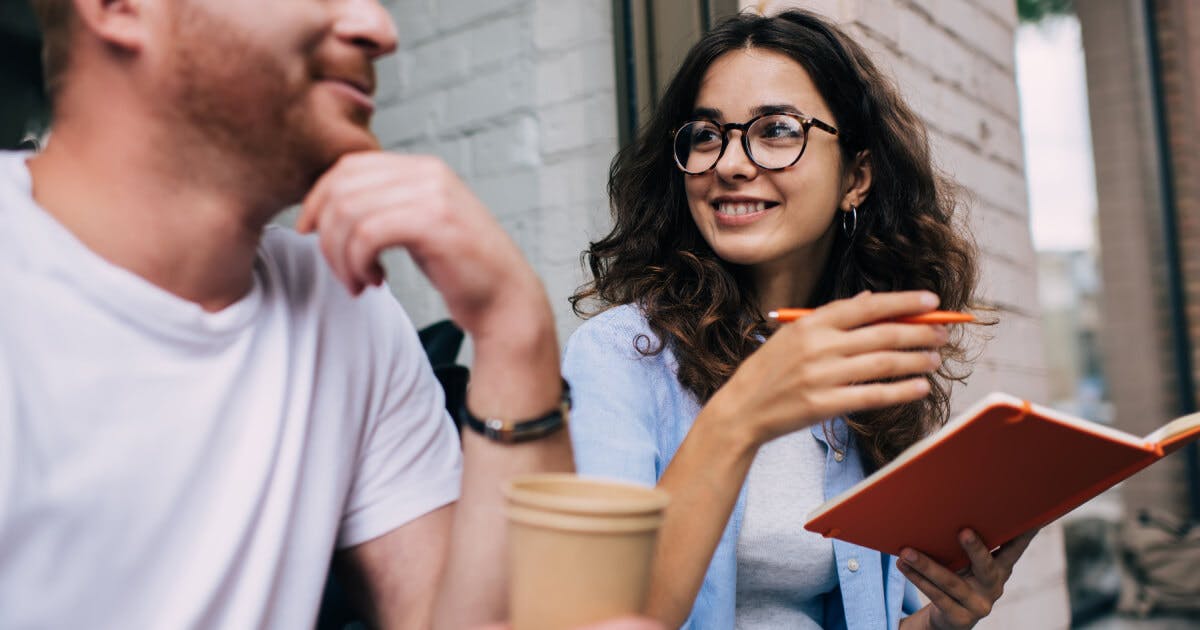 Homem e mulher conversam enquanto estão sentados em um café.