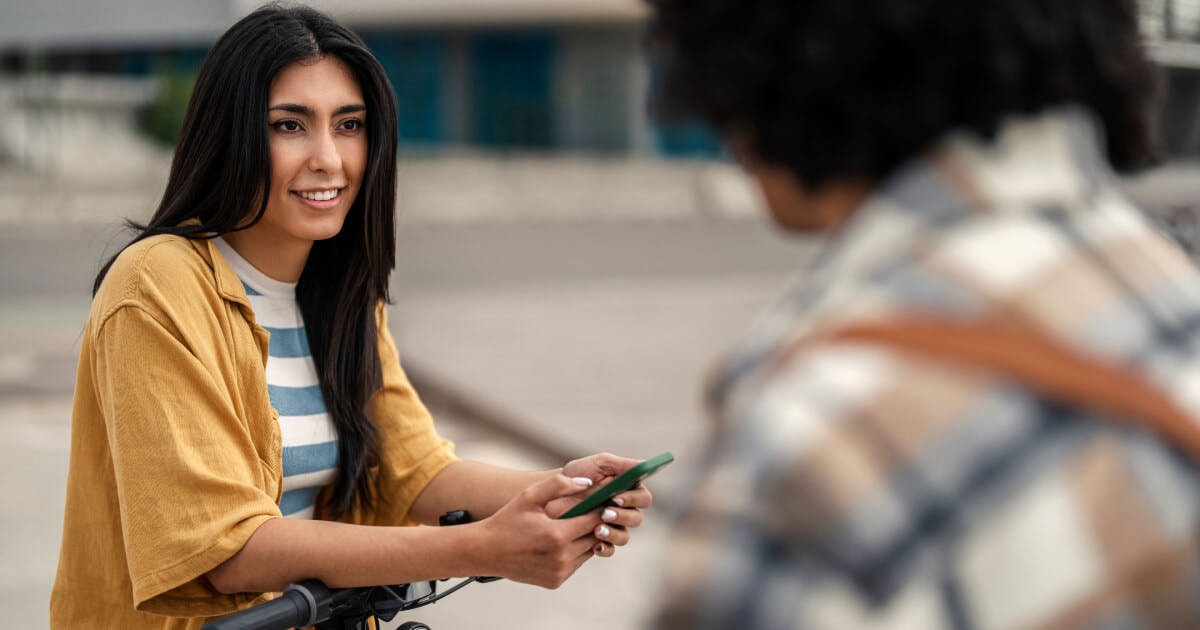 Mulher segurando um celular enquanto conversa com um homem.