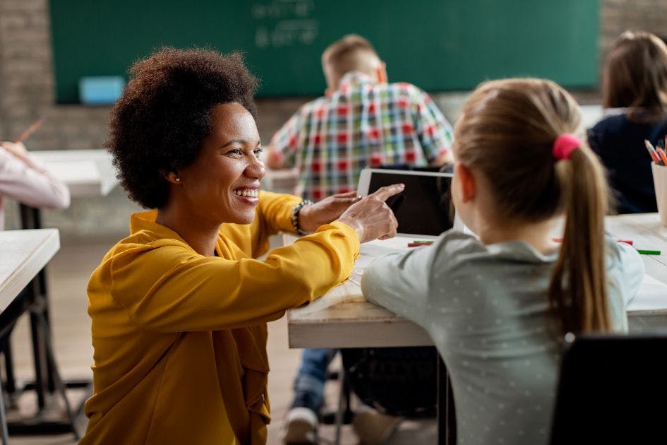 Professora auxiliando a aluna em sala de aula.