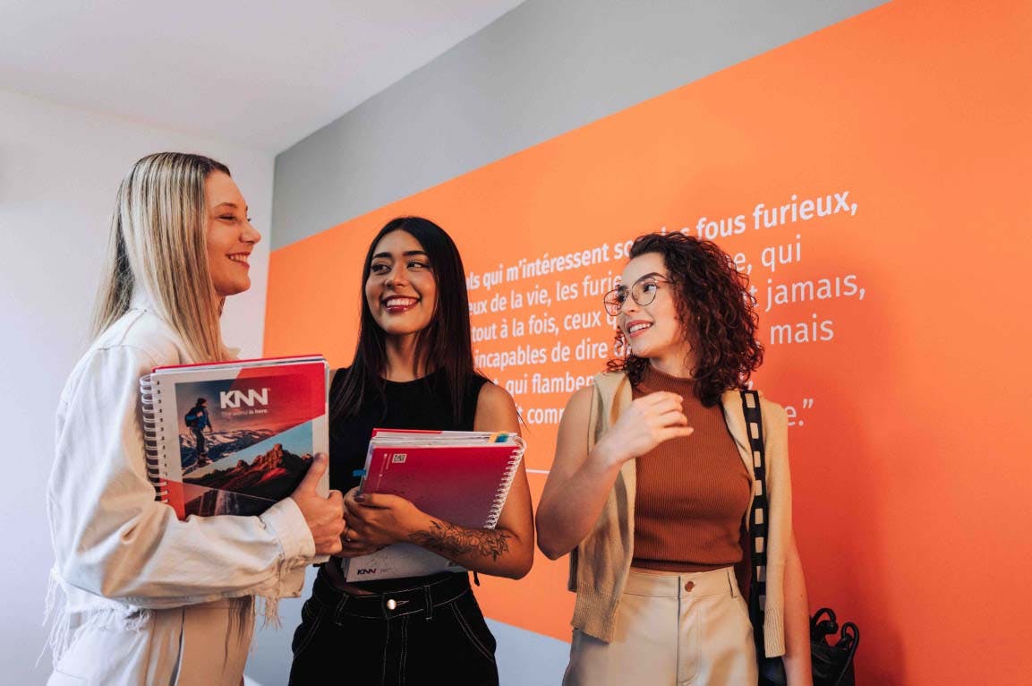 3 mulheres segurando livro didático 