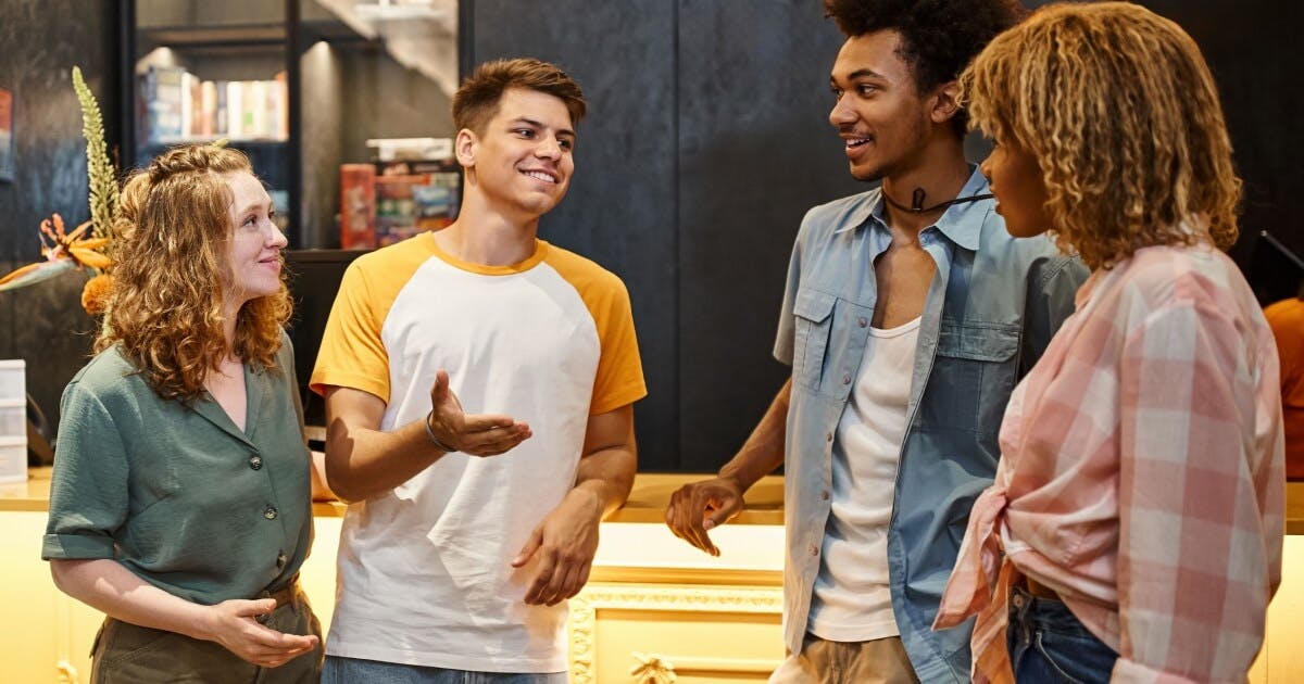 Quatro jovens conversando animadamente em um bar, rodeados por um ambiente descontraído e acolhedor.