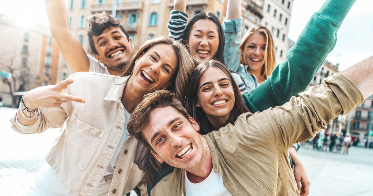 Grupo de jovens se divertindo na cidade, sorrindo e interagindo em um ambiente urbano vibrante e animado.