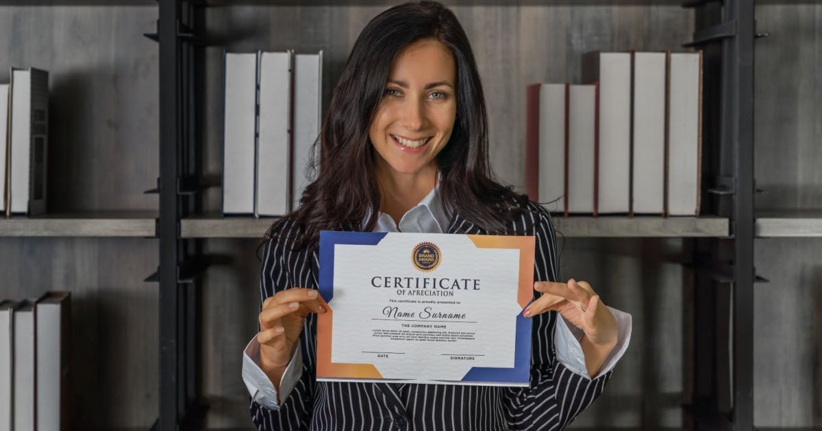 Uma mulher de cabelo preto segurando um certificado com as duas mãos.