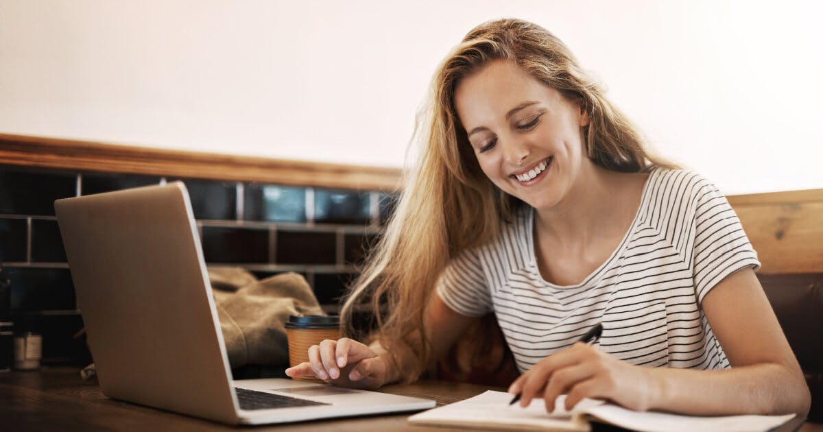 Uma mulher sorrindo enquanto trabalha em seu laptop.