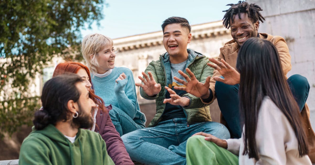 Grupo de jovens sentados na calçada, conversando e compartilhando momentos de descontração e amizade.