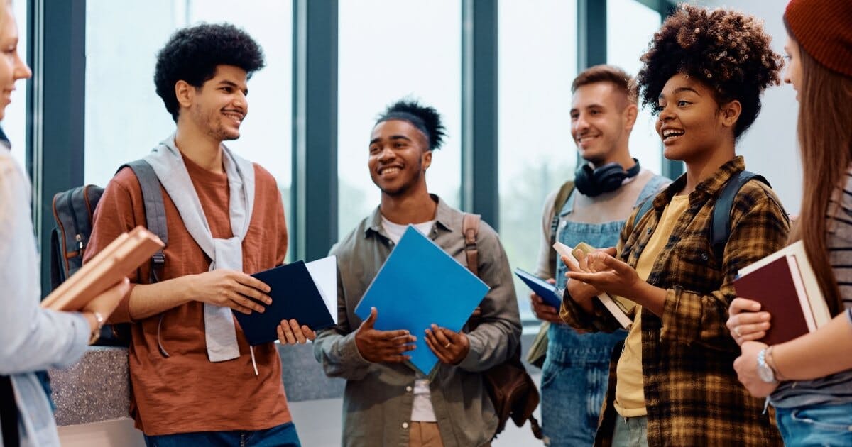 Grupo de jovens reunidos em um corredor, interagindo e sorrindo, transmitindo um ambiente de amizade e descontração.